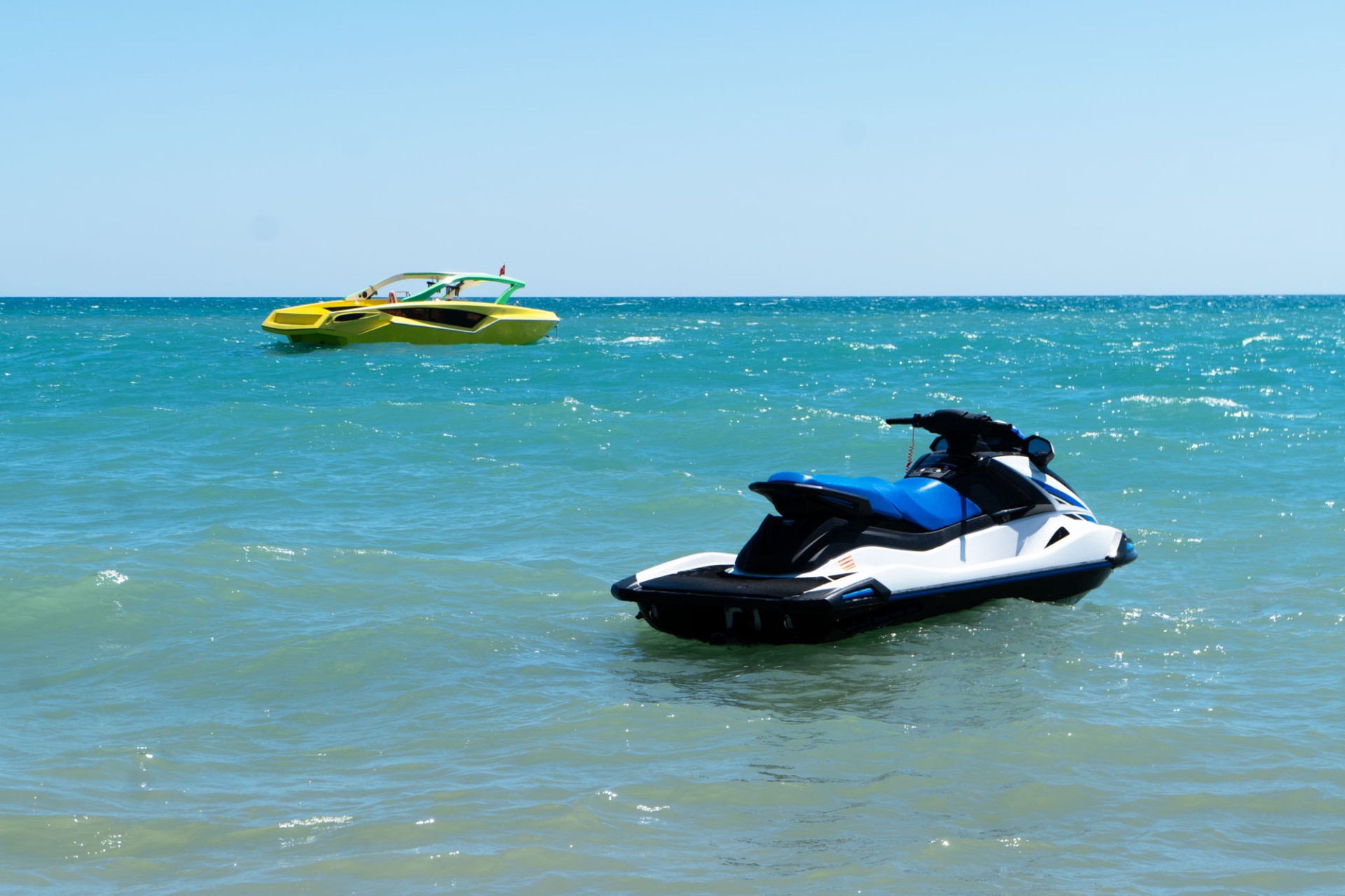 Blue sea with a jet ski and speedboat floating on the sea. Water scooter and speed boat is in the blue sea.